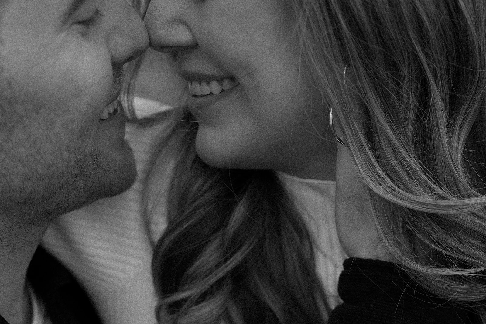 A black and white photo of a couple sharing a kiss during their documentary engagement session.