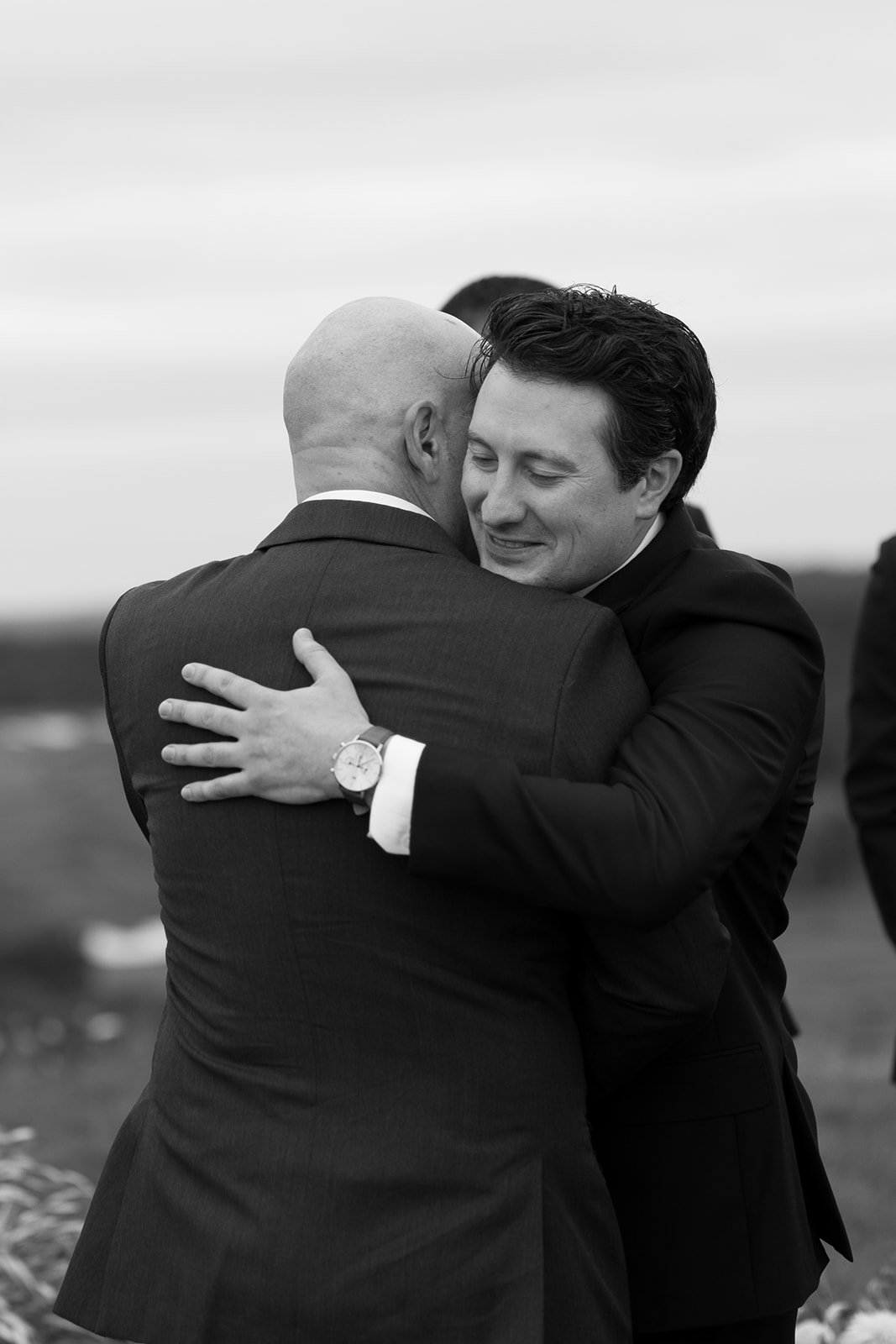 groom and wedding guest hugging 