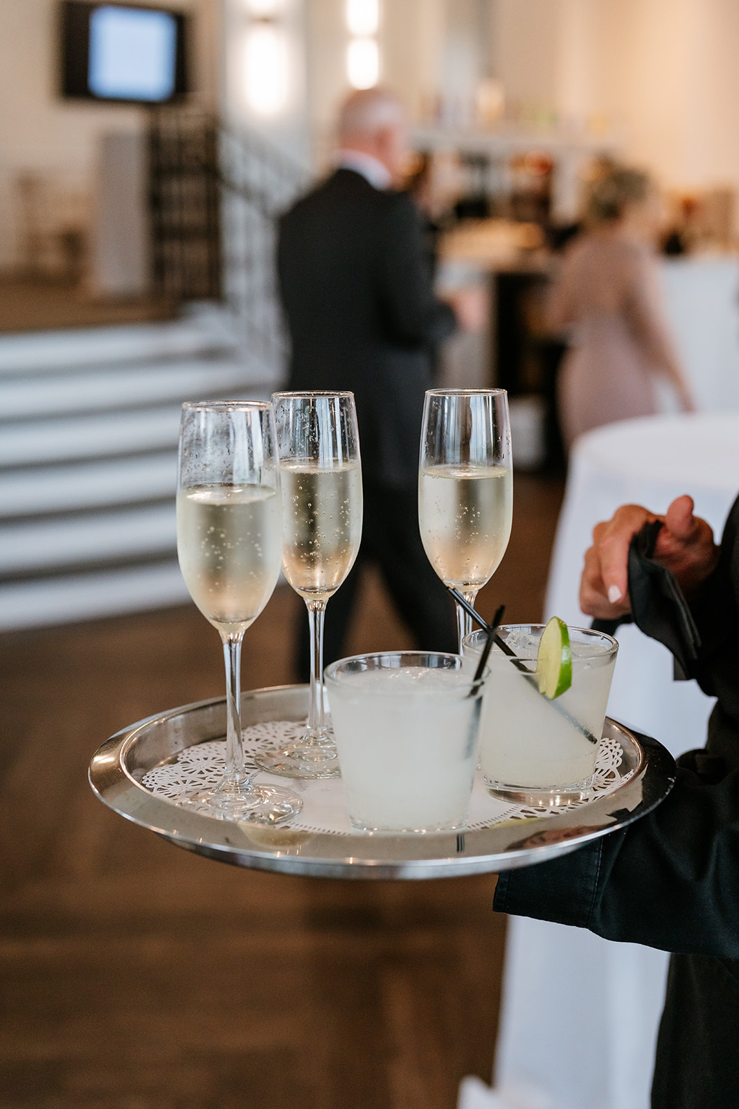 A waiter gracefully holds a tray with three glasses of champagne, ready to serve the sparkling beverages to guests.