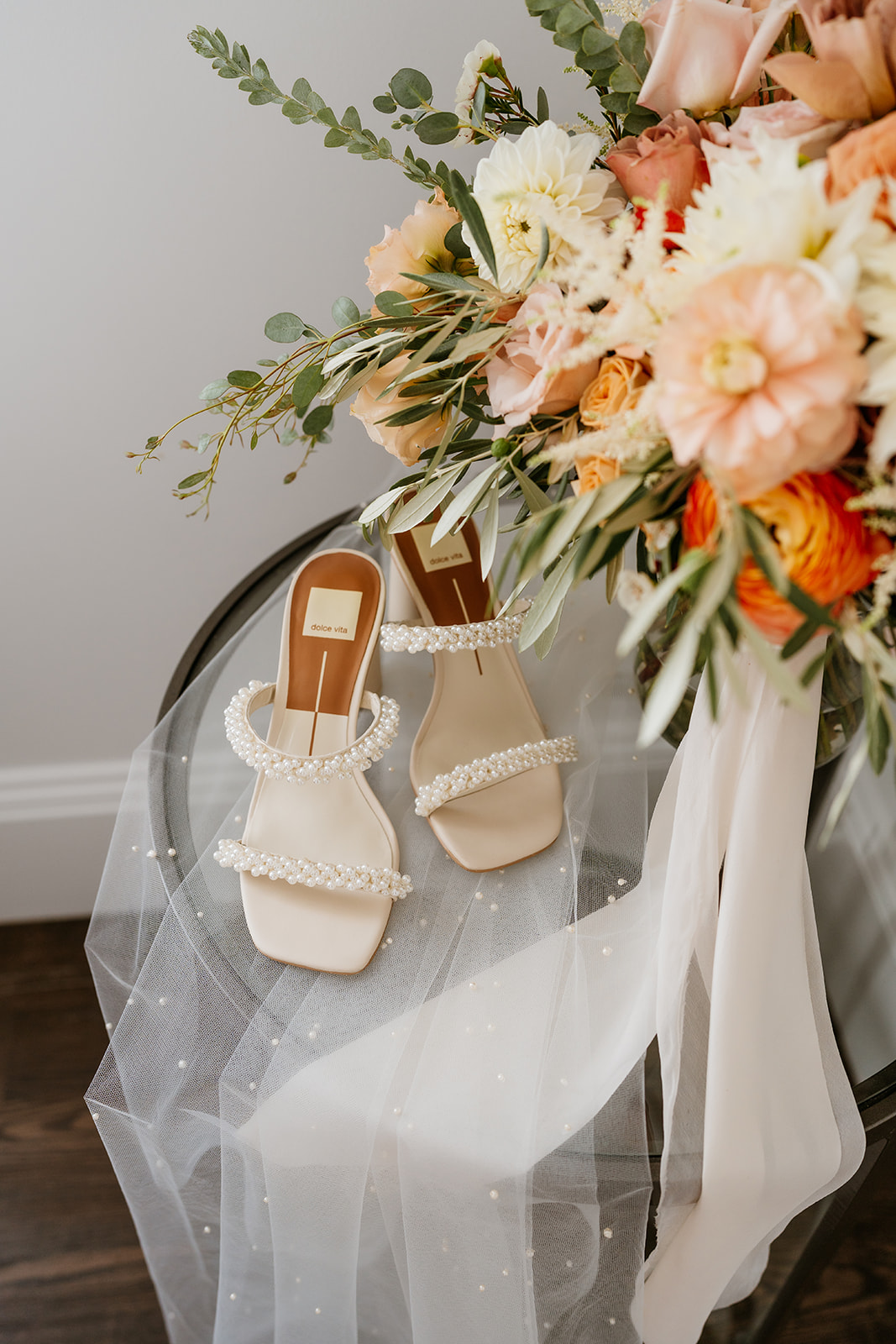 Summer-themed bridal bouquet featuring vibrant flowers accompanied by elegant white bridal shoes sitting on a table
