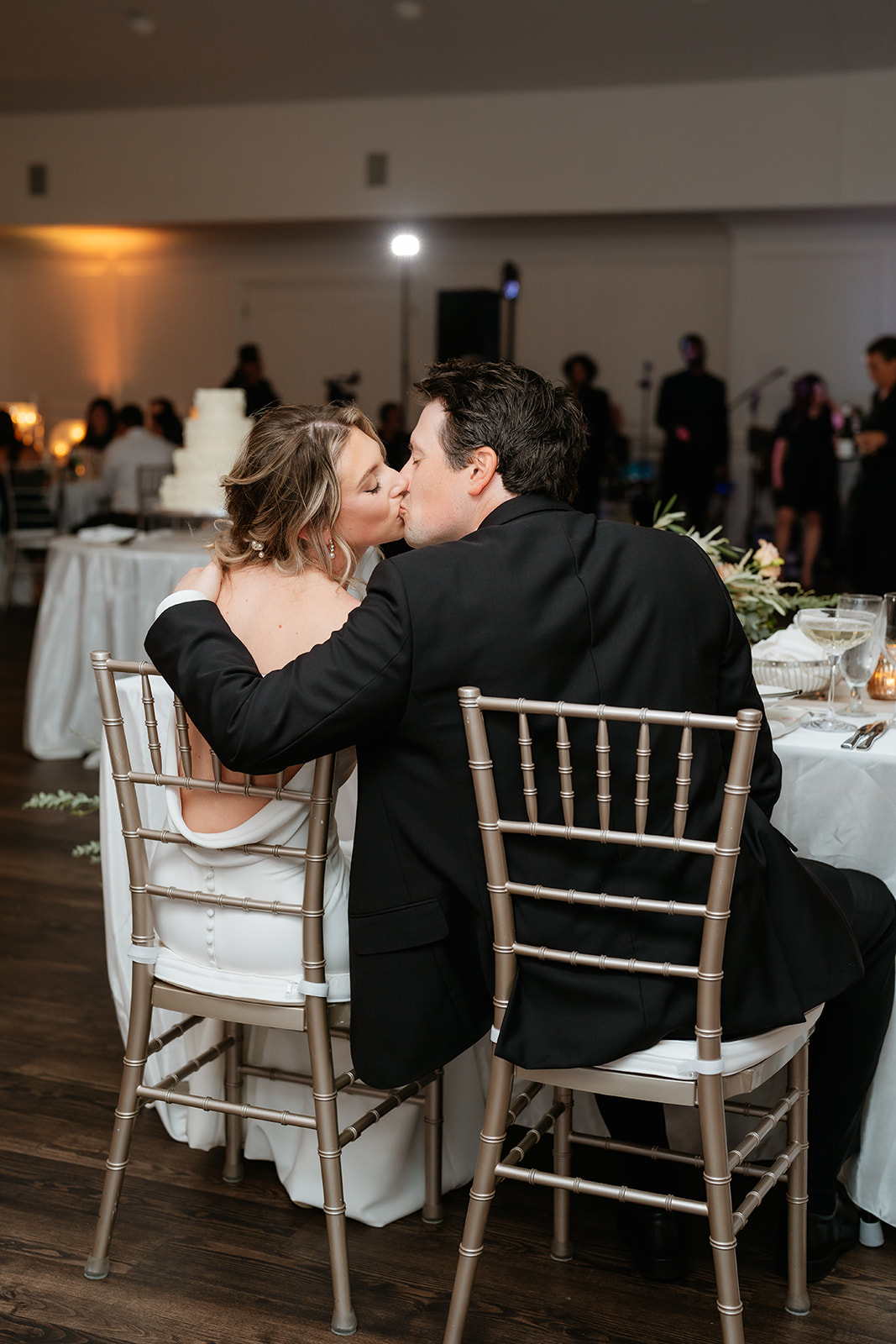 A happy couple at their wedding reception at Granite Links sitting together at a beautifully decorated table while kissing