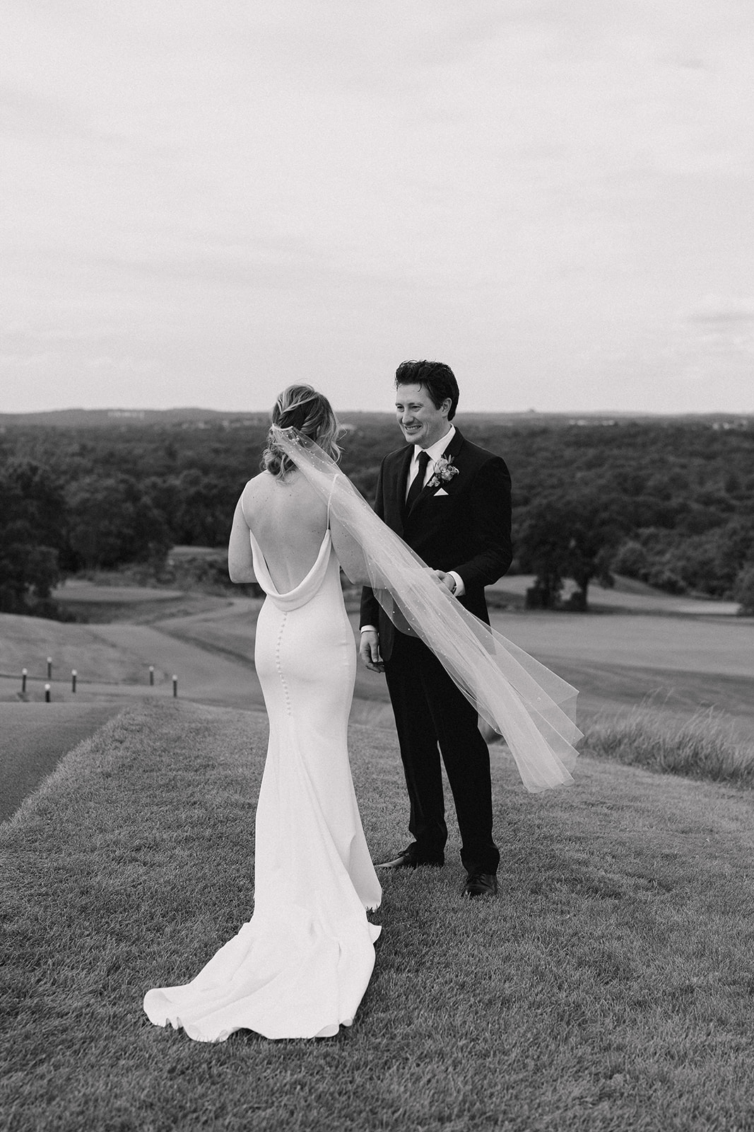 Black and white photo of bride and groom on a hill