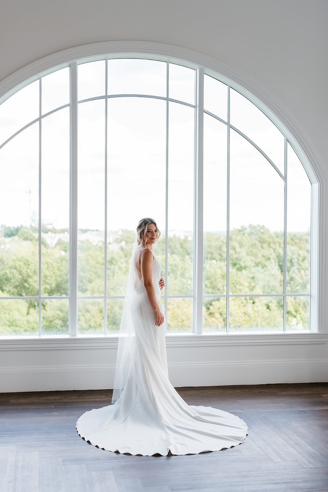 A bride stands in front of a large window at Granite lakes