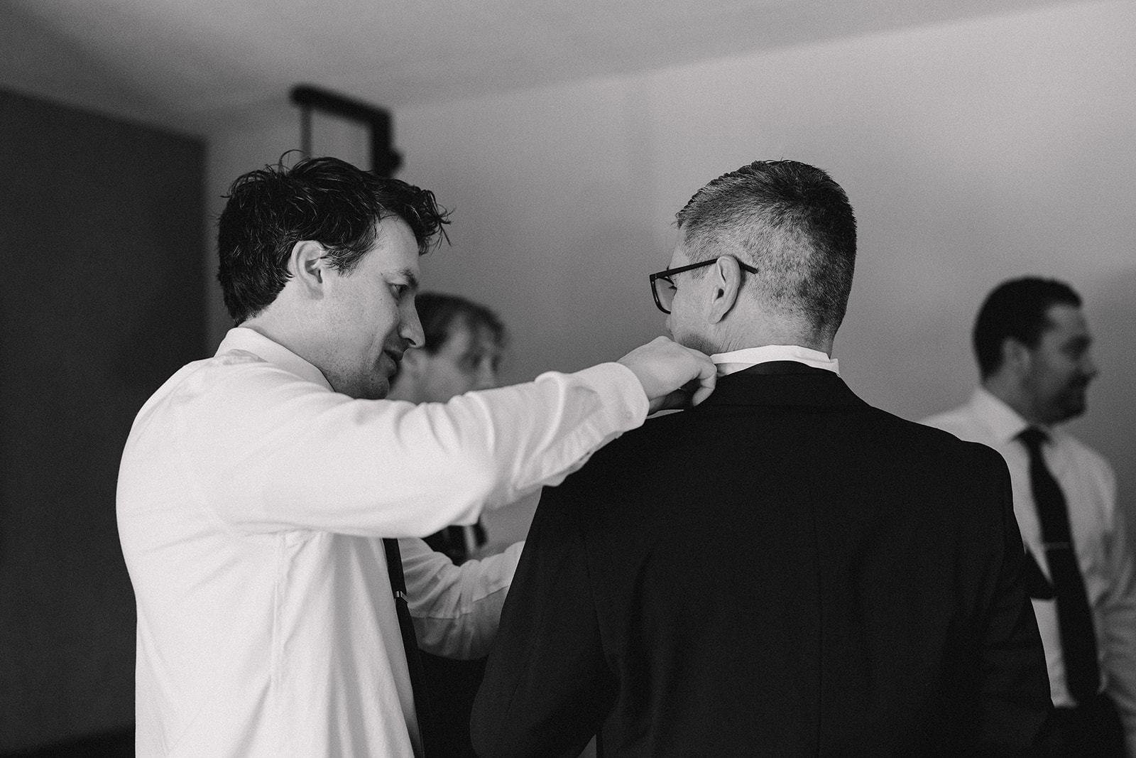 Groom adjusting groomsmen collar