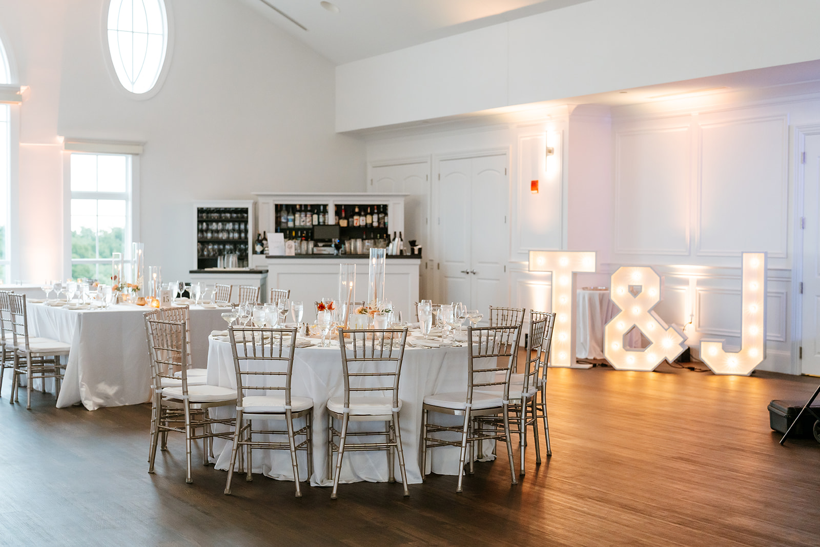 A beautifully set wedding reception table with elegant white linens and chairs, ready for a celebration of love.