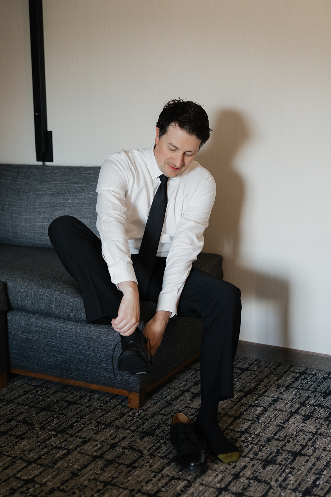 Groom sitting on a couch and putting on his shoes