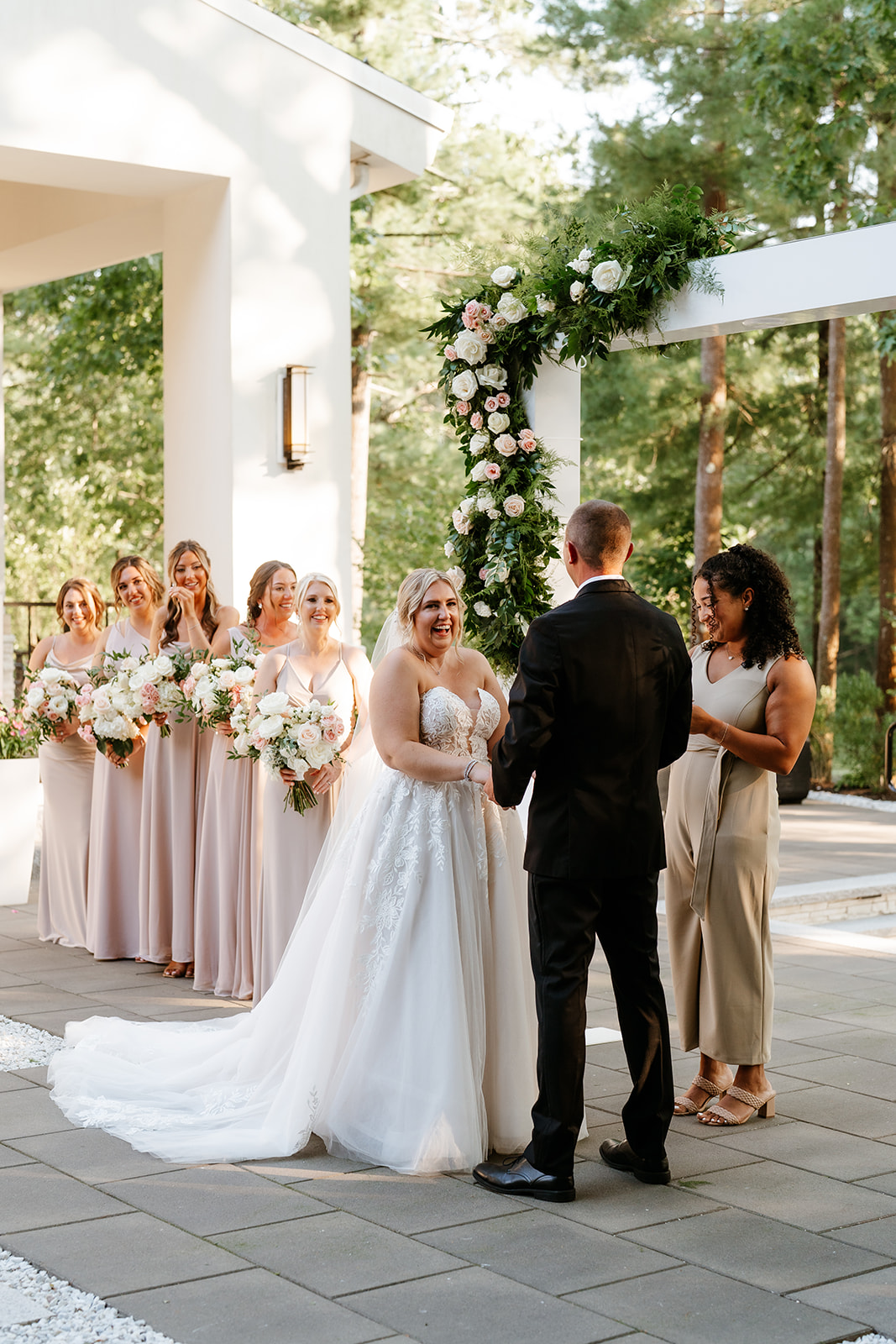 A bride and groom hold hands at an outdoor wedding ceremony while surrounded by their bridal party at Lakeview Pavilion.
