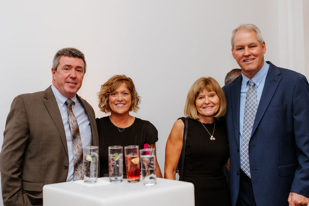 Four adults standing beside a small table with drinks, posing for a photograph at a wedding at Lakeview Pavilion