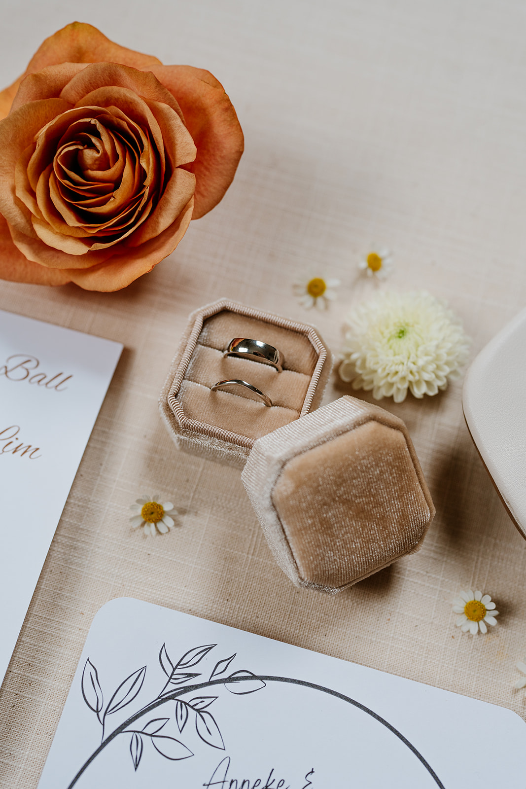 Flat lay of elegant wedding stationery surrounded by floral decorations and ribbon.