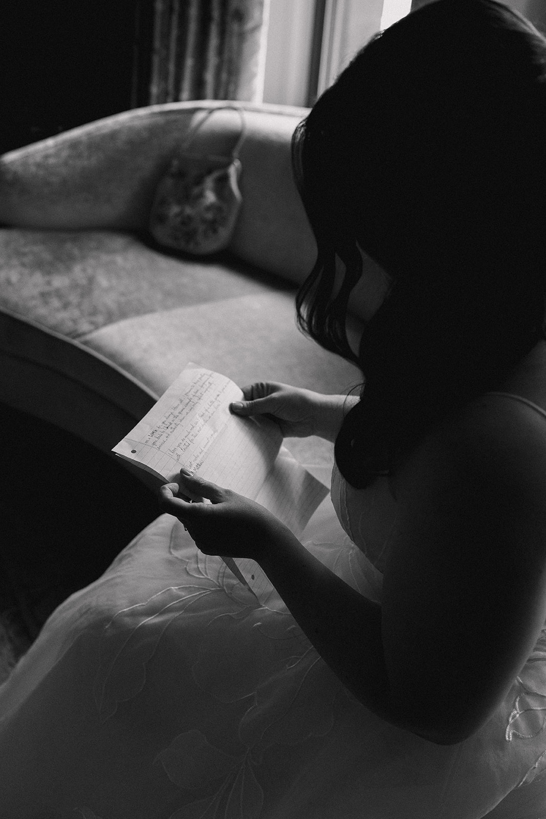 A woman in a dress reading a handwritten letter from her soon to be husband at The Estate at Moraine Farm