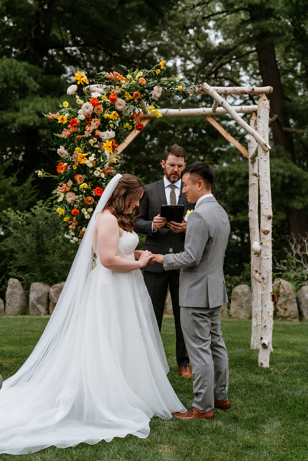 A wedding ceremony in progress with a couple at the altar, an officiant reading, and guests watching at the estate at moraine farm