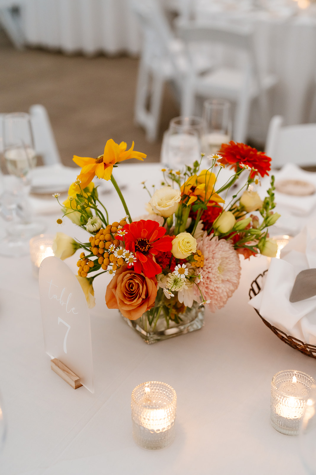 Elegant table setting featuring a vibrant floral centerpiece and candlelight with a table number sign.