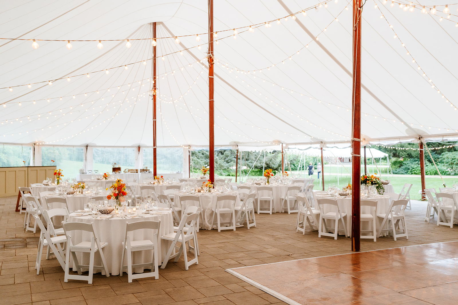 Elegant outdoor tented wedding reception area with string lights and decorated table at the estate at moraine farm