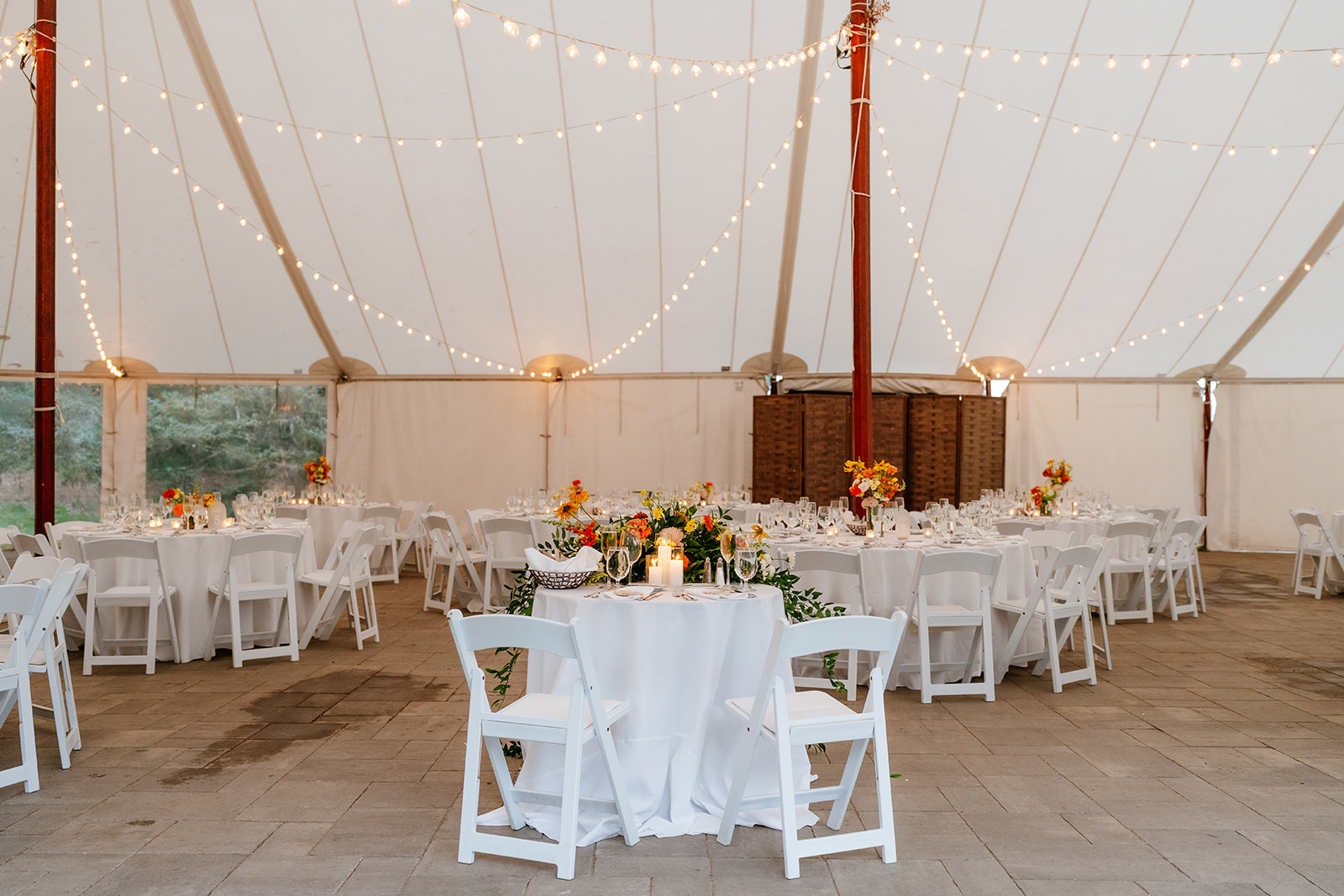 Elegant outdoor tented wedding reception area with string lights and decorated table at the estate at moraine farm
