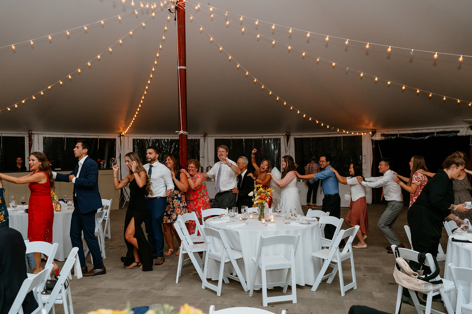 Group of people happily participating in a conga line dance at estate at moraine farm wedding