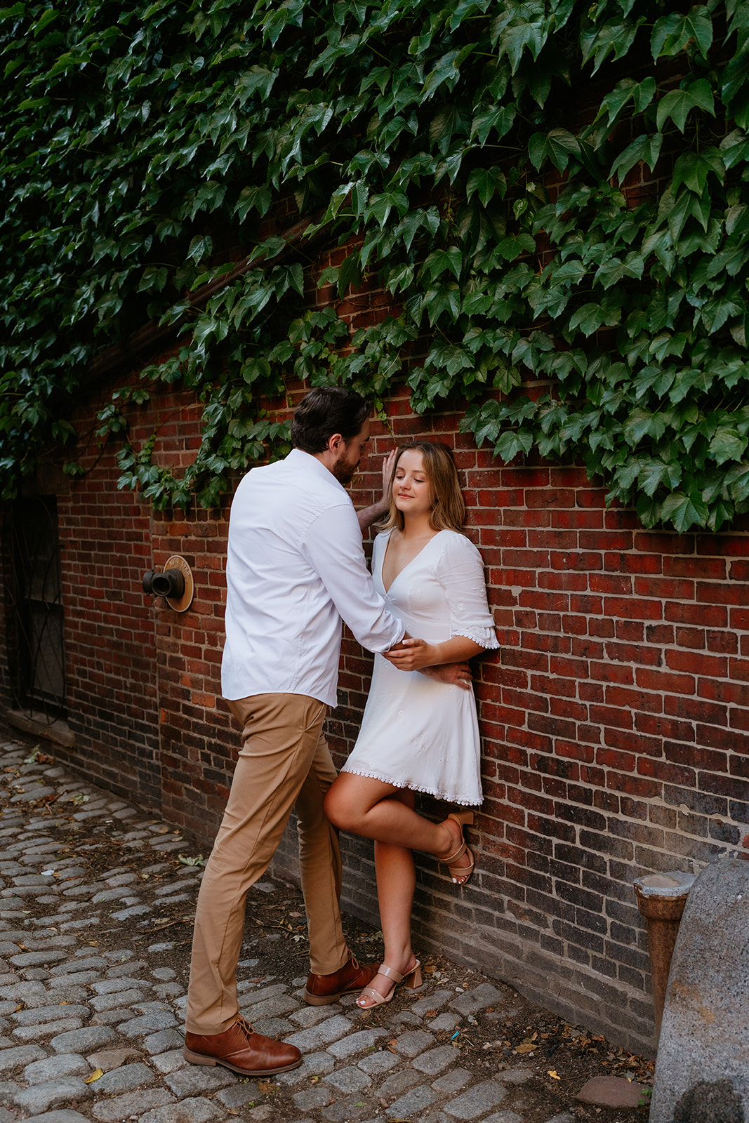 Couple holding one another against a brick wall posing for their Beacon Hill couple session