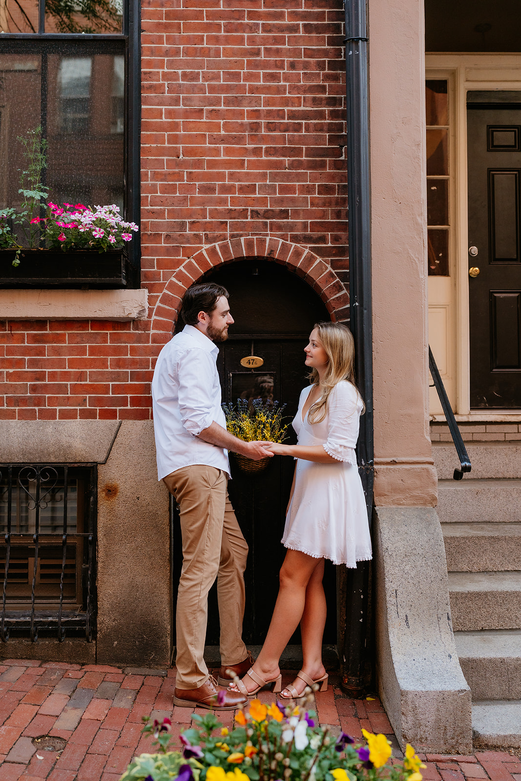 Couple holding hands standing in front of a brick building in Boston for their Beacon Hill couples session