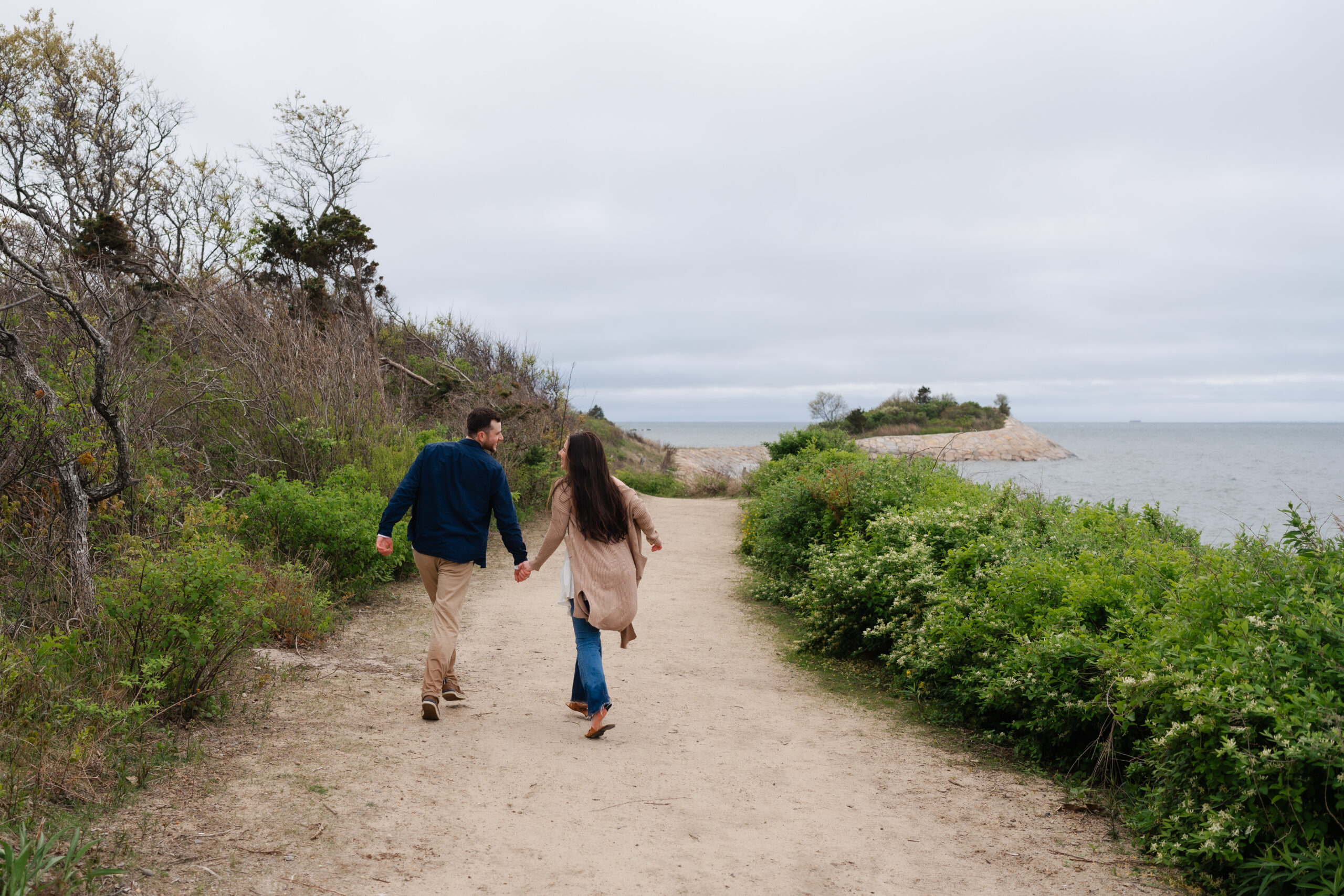 Engaged couple walking holding hands at the Knob in Cape Cod