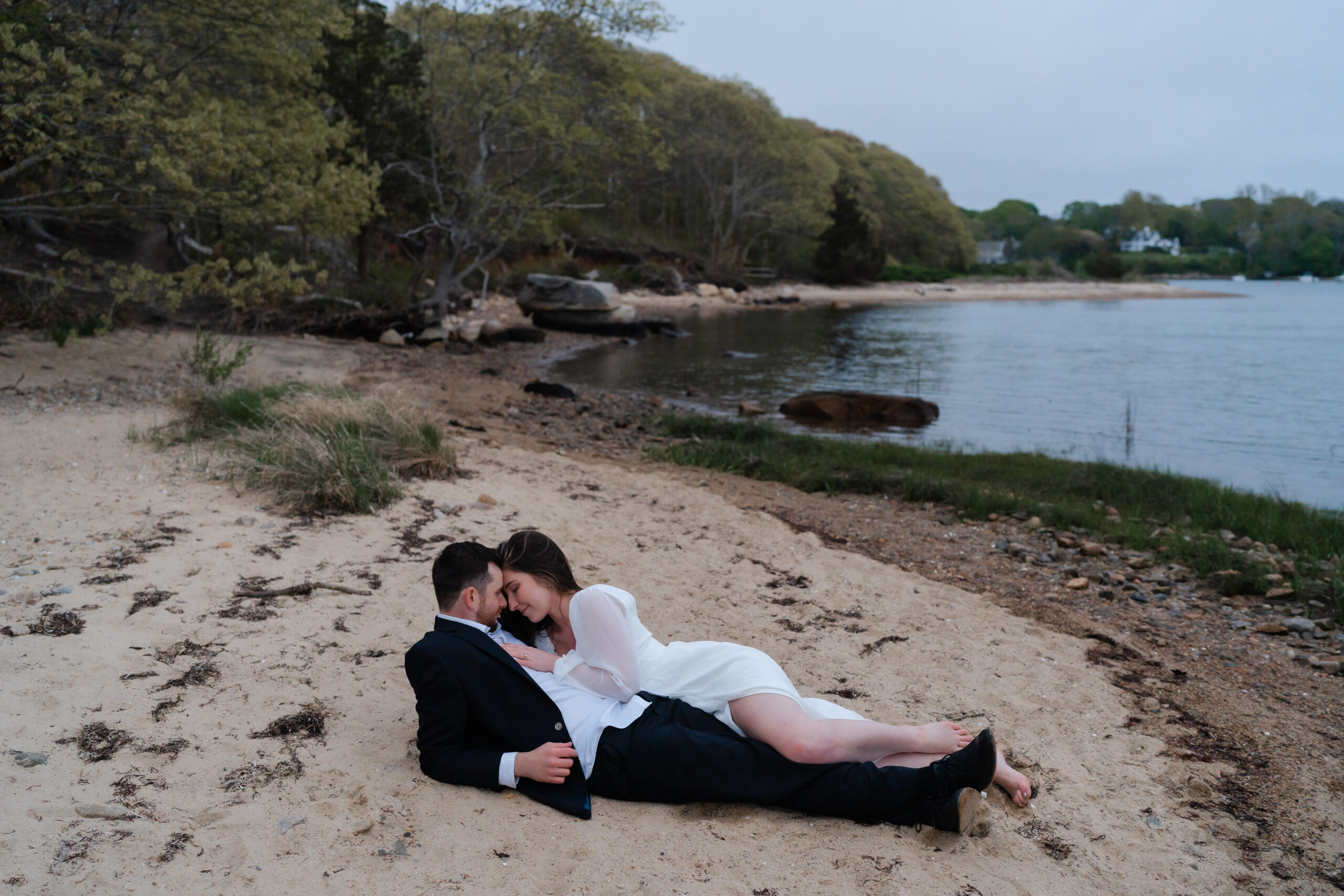 Engaged couple laying on the beach holding one another