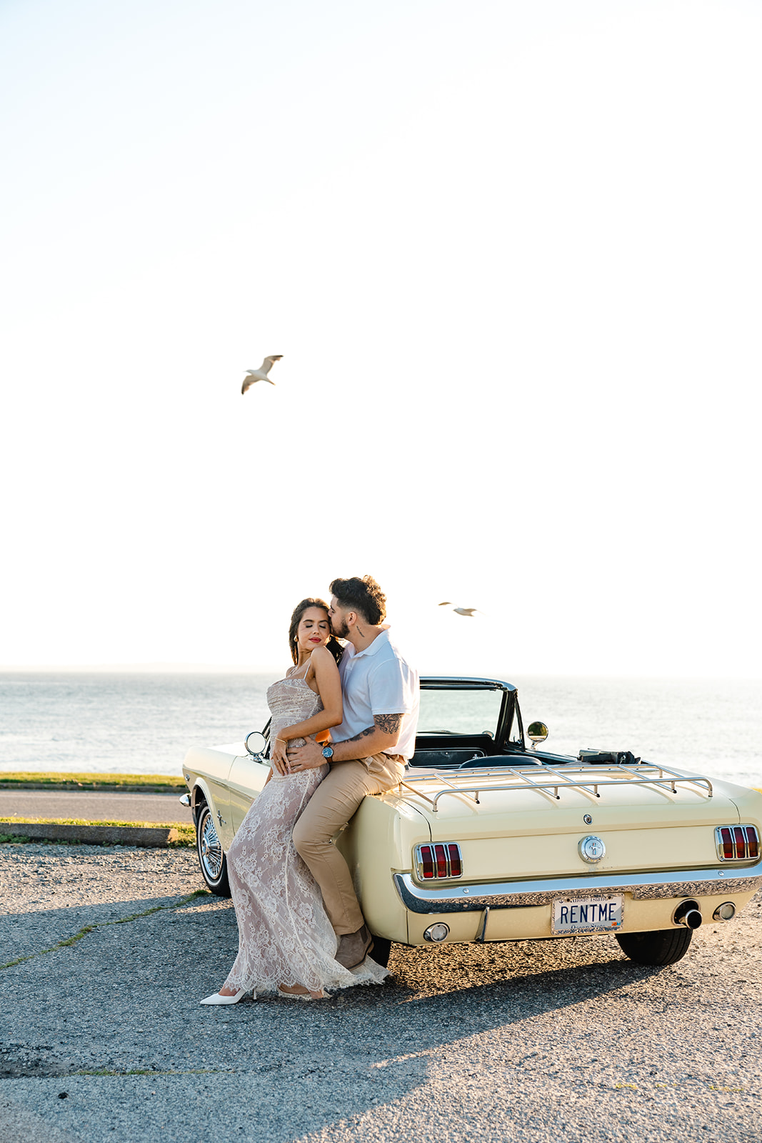 Newly engaged couple leaning on a classic car posing for their classic car engagement photos