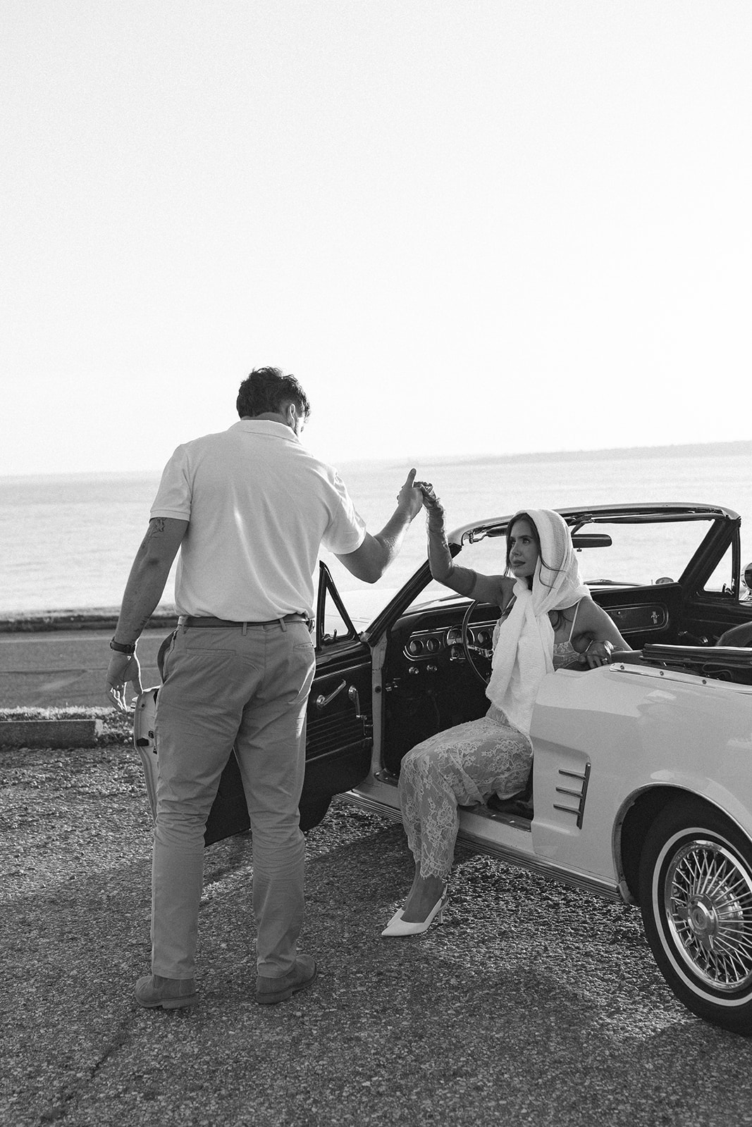 Black and white photo of Newly engaged couple posing in a vintage car for their classic car engagement photos 