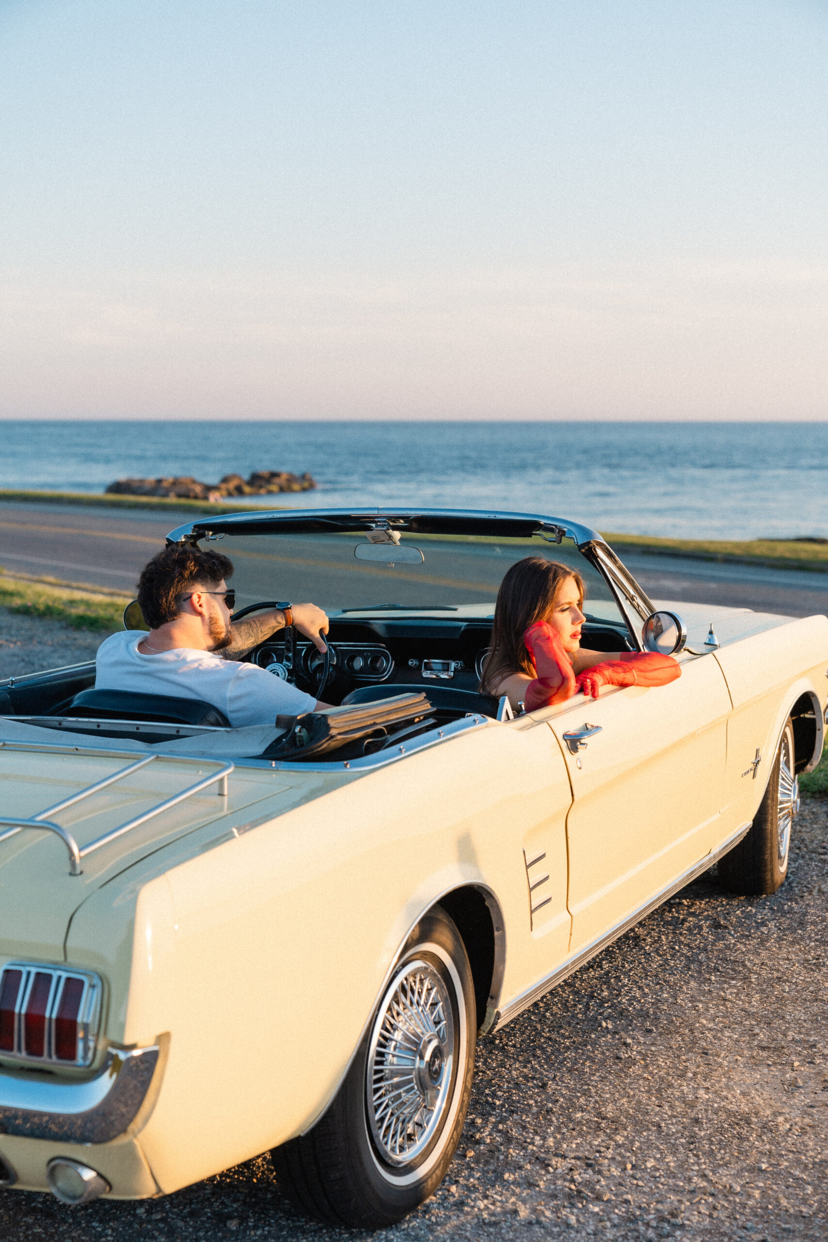 Newly engaged couple driving a classic car at Ocean Drive in Newport