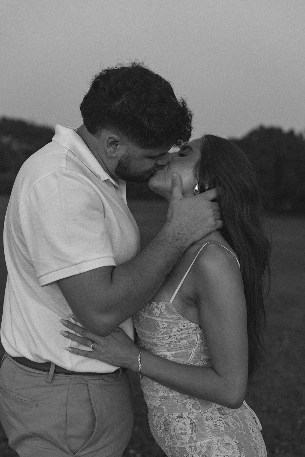 Black and white photo of newly engaged couple kissing 