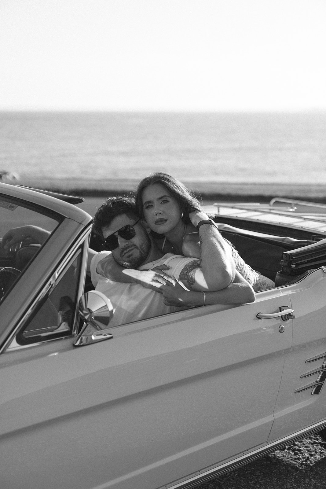 Black and white photo of Newly engaged couple posing in a vintage car for their classic car engagement photos 