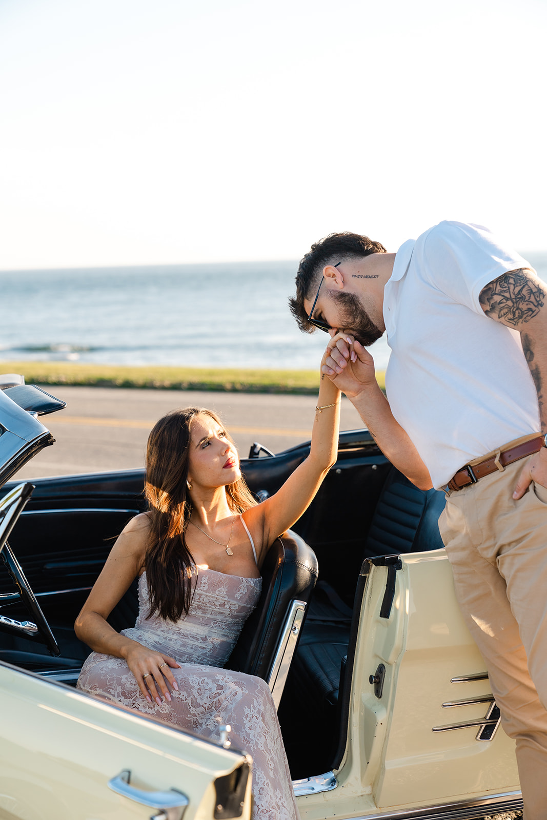 Fiance kissing soon to be wifes hand in a vintage car 