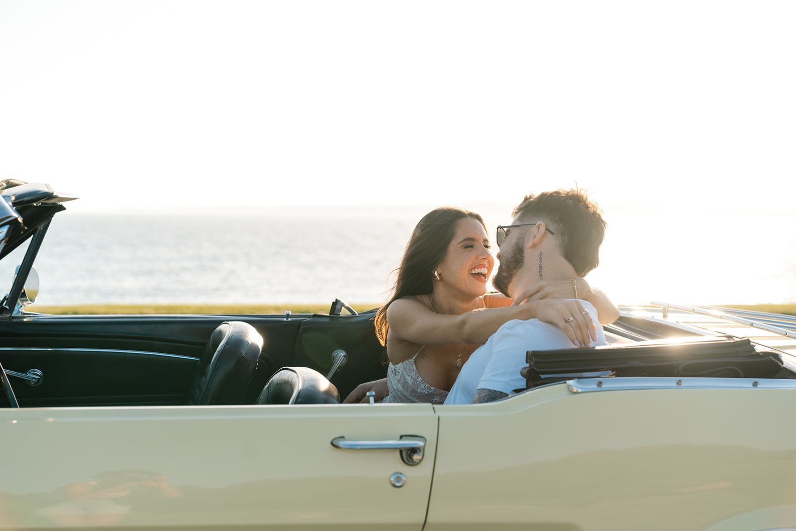 Newly engaged couple sitting in a classic car smiling for their classic car engagement photos