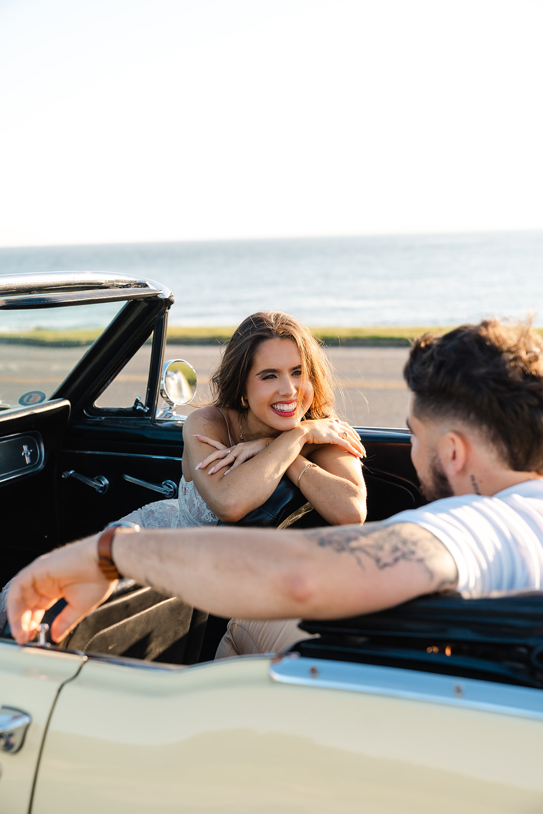 Newly engaged couple smiling at eachother during their classic car engagement photos 