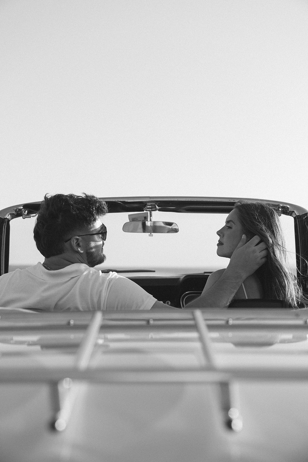 Black and white photo of Newly engaged couple posing in a vintage car for their classic car engagement photos