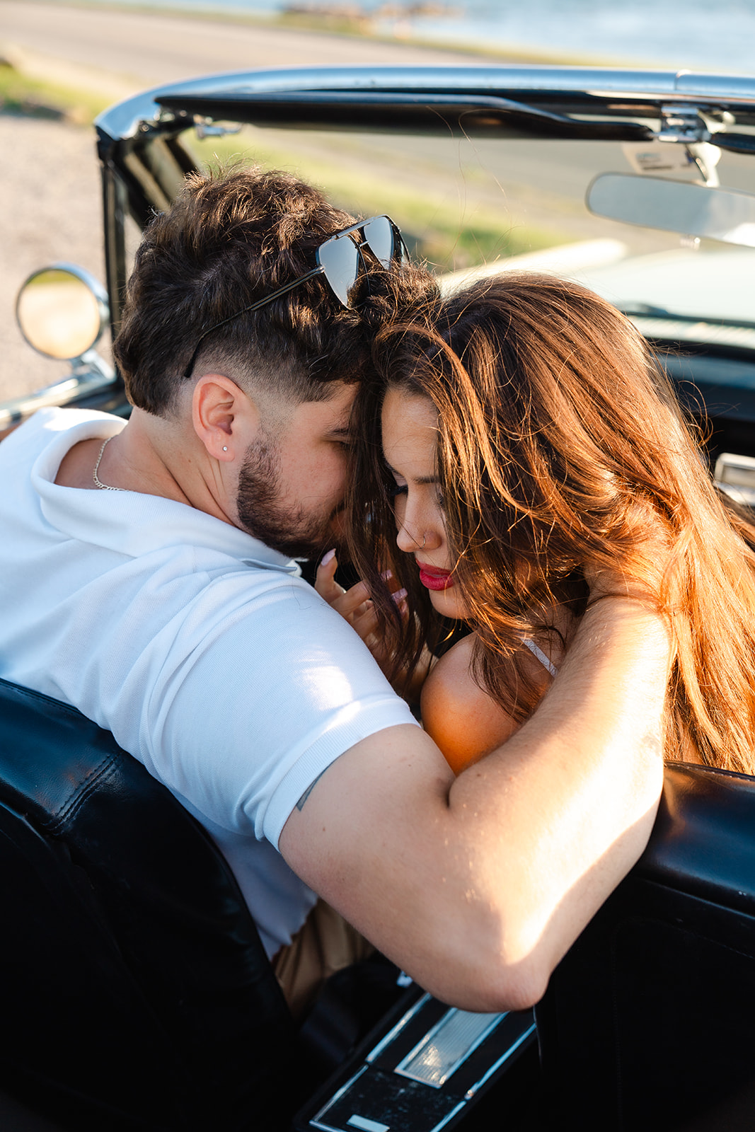 Newly engaged couple embracing in a vintage car