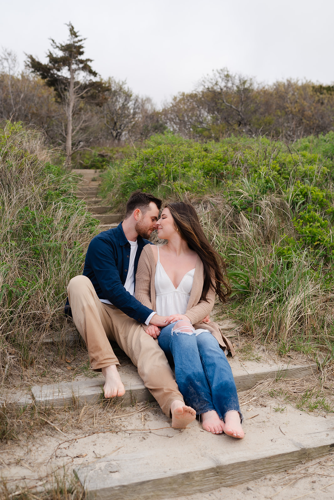 Engaged couple sitting on beach stairs looking into eachothers eyes