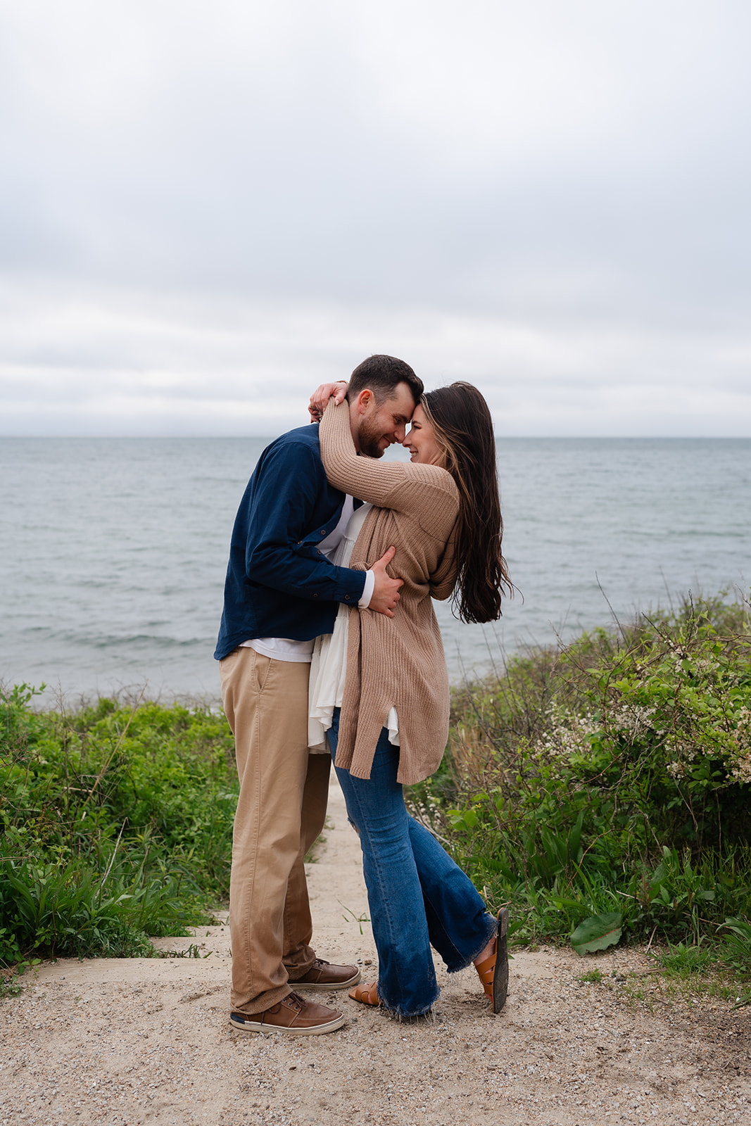 Engaged couple hugging and holding one another while smiling 