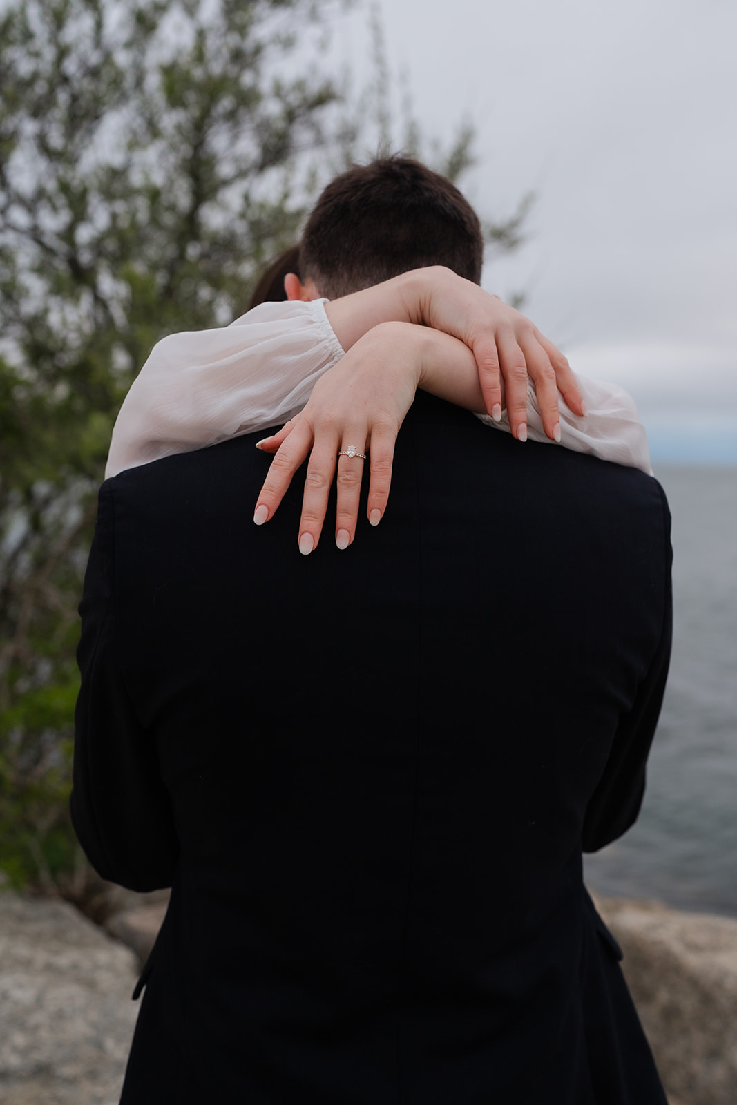 Engaged couple hugging one another showing of the fiances engagement ring