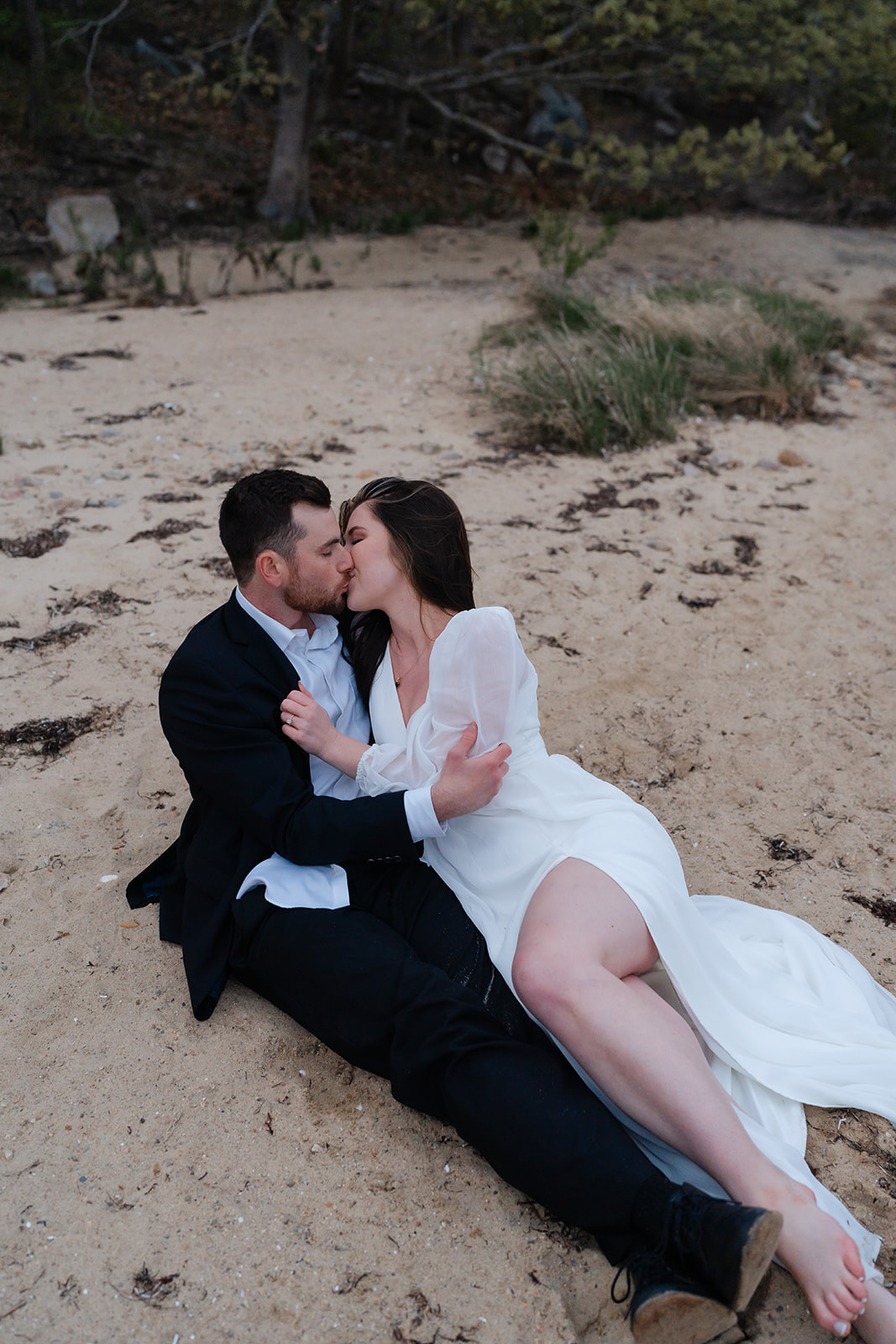 Engaged couple laying on the beach kissing eachother