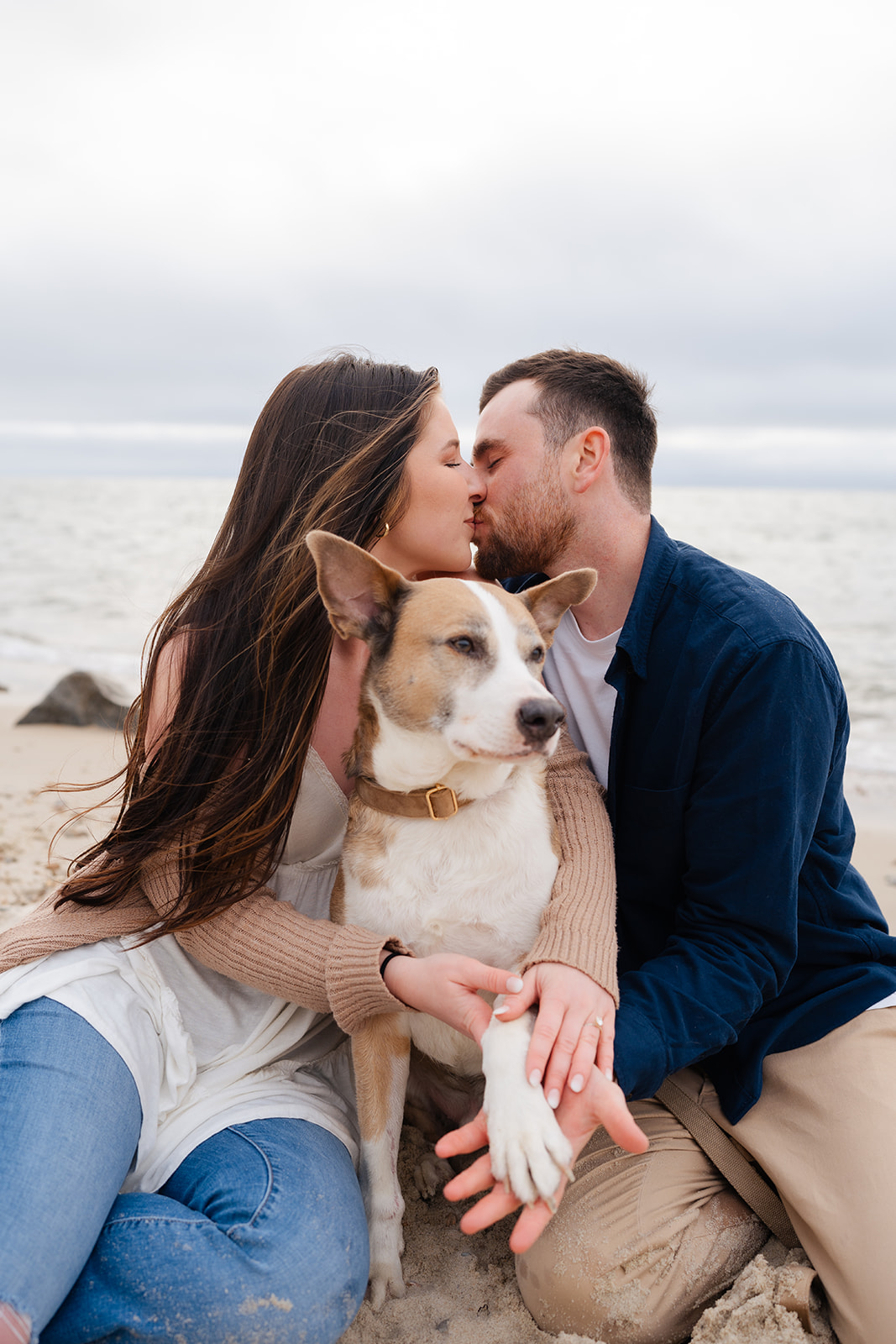 Engaged couple kissing while they hold their puppies during their Cape Cod engagement