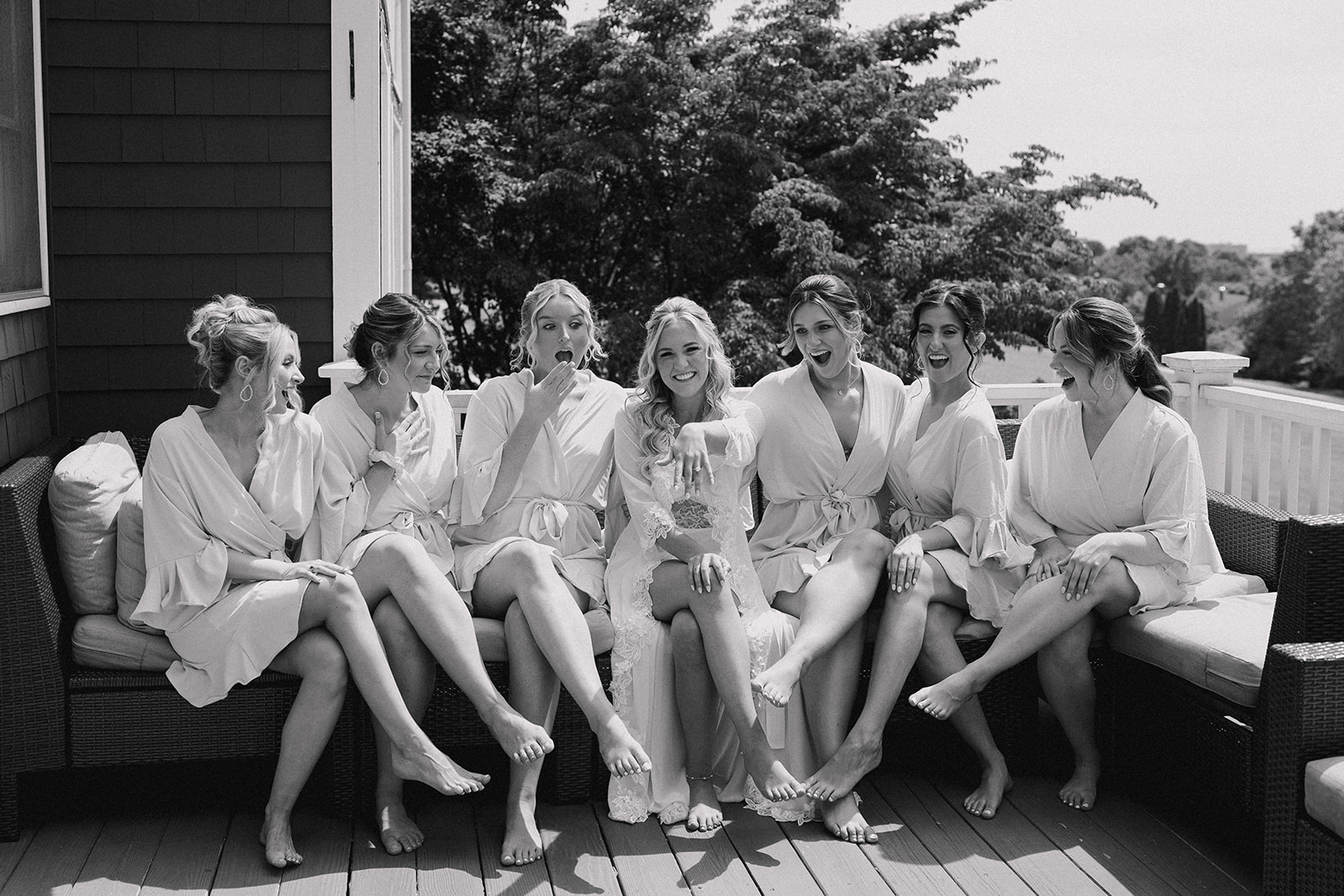 bride and bridesmaids outdoor at the porch sitting down while the bride showing off her ring