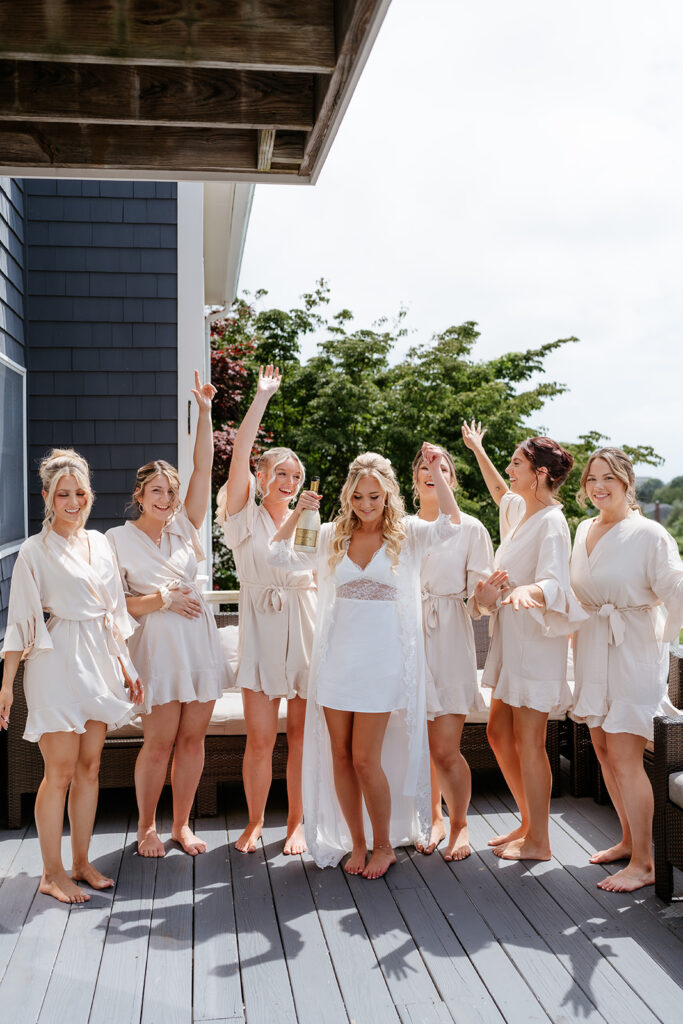 bride and bridesmaids celebrating with their getting ready ropes with champagne 