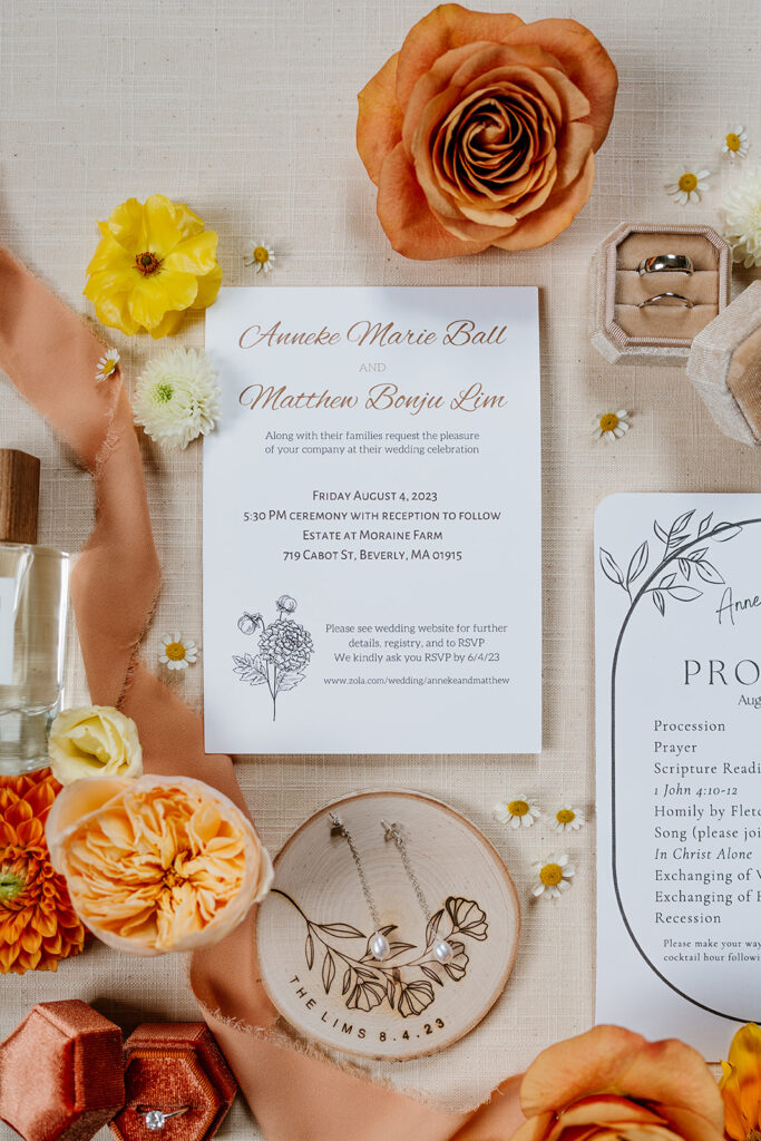 Colorful flat lay of the bride's and groom's items, her perfume, her earrings and her rings. Also with formal invitation card