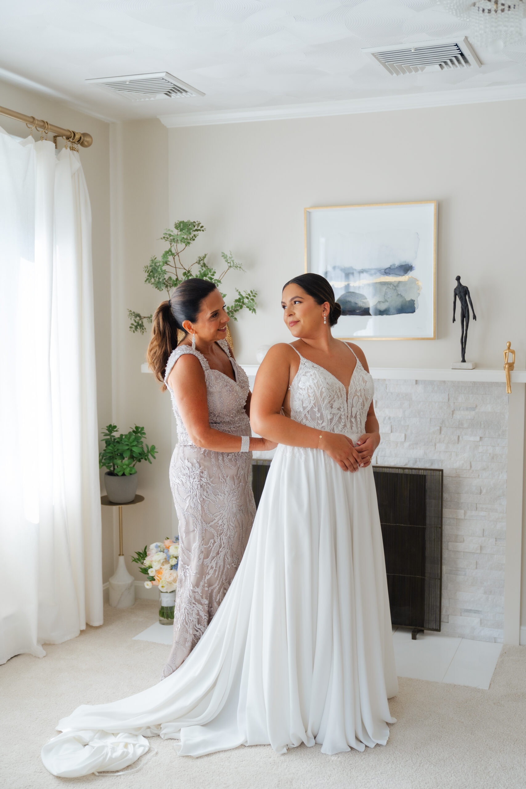 Mother of the bride helping the bride put on her dress