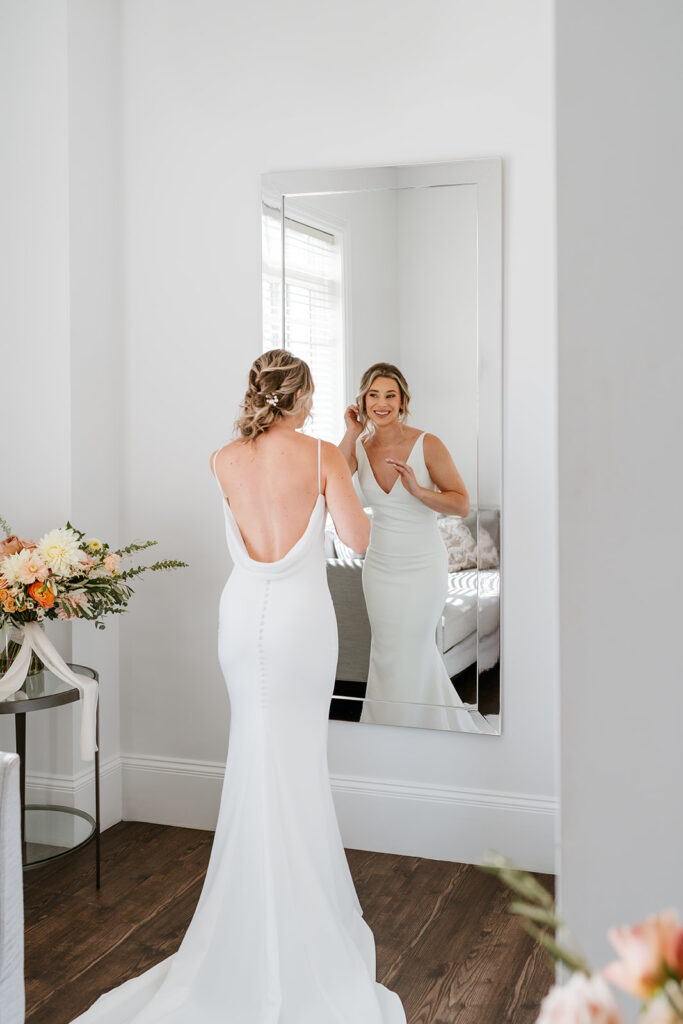 bridal portrait of her getting ready looking at herself through the mirror