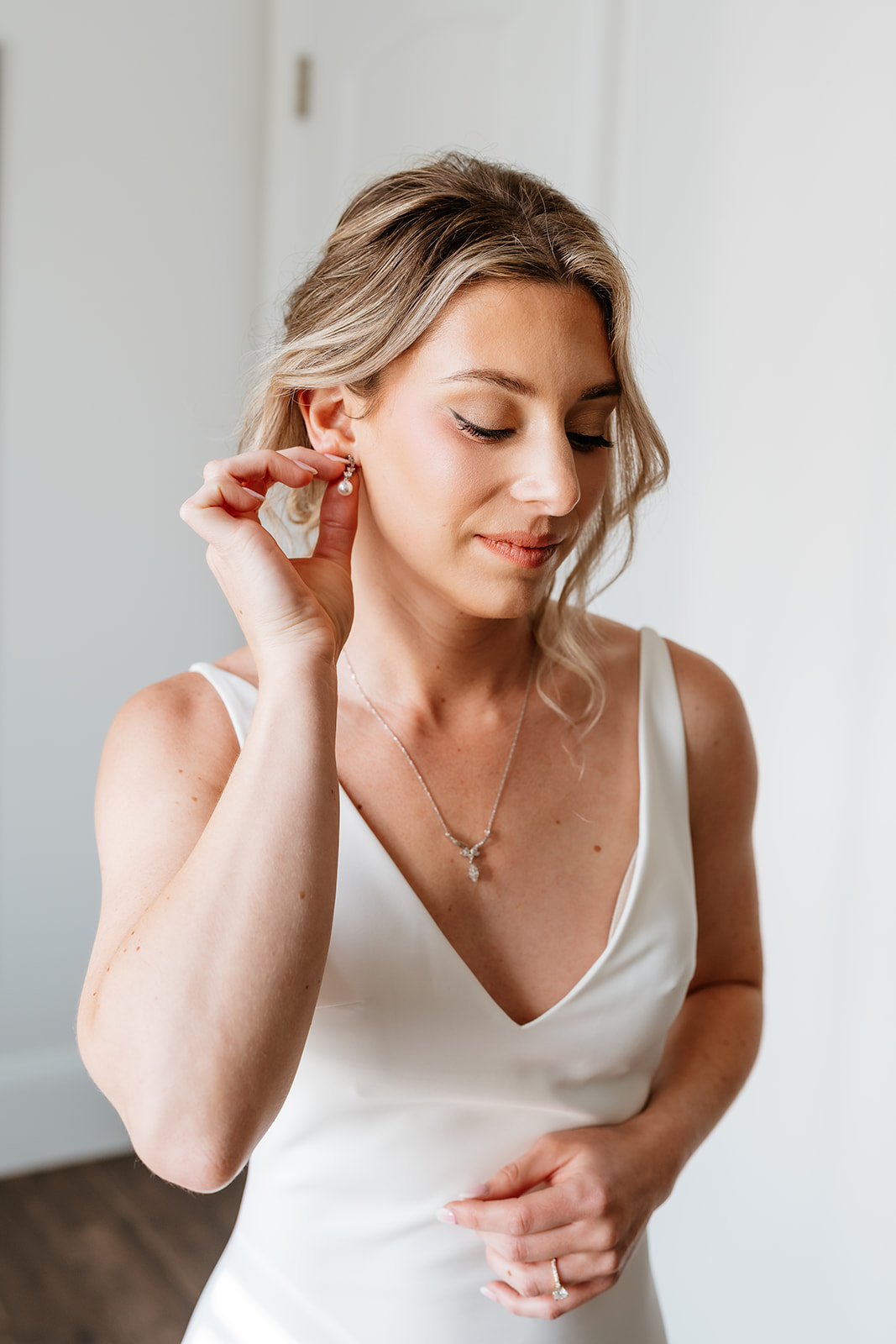 a getting ready wedding photo of the bride putting earrings on 