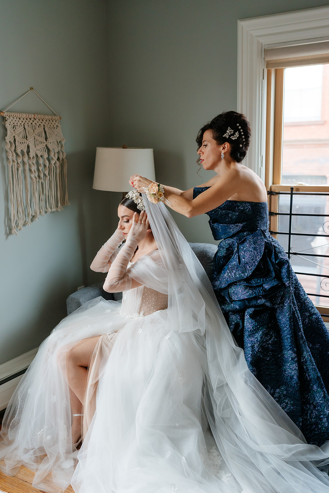 mother of the bride helping the bride to put the veil on