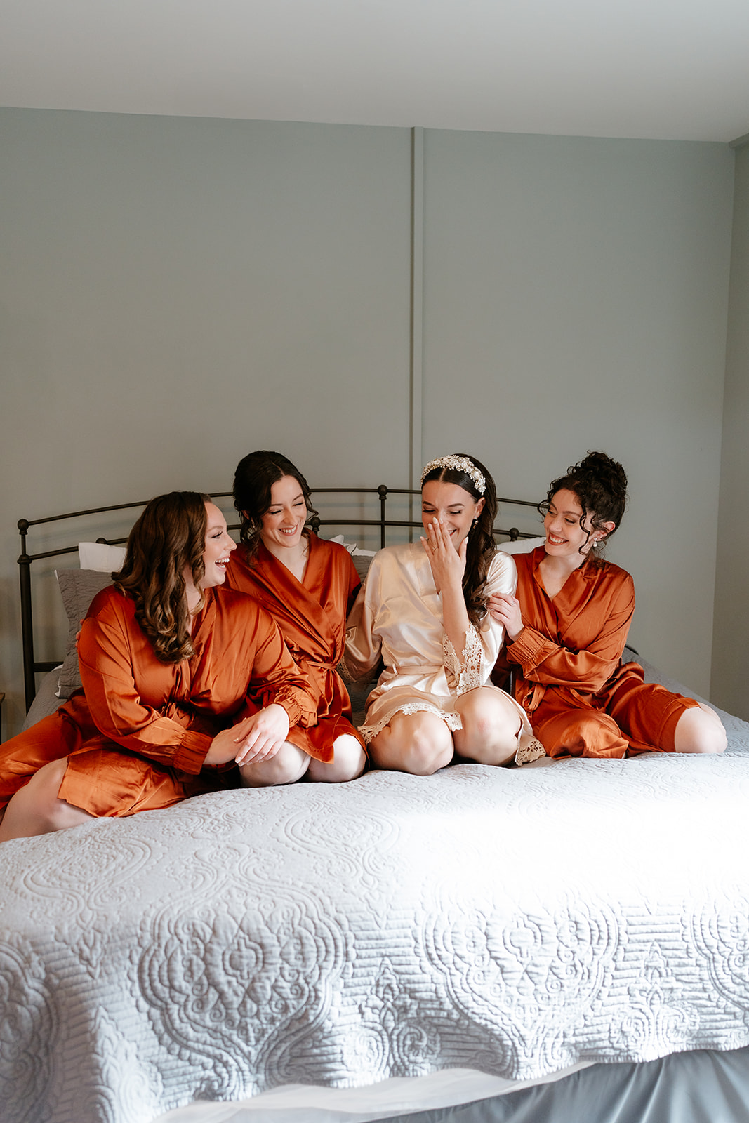 bride and bridesmaids sitting on the bed with getting ready ropes