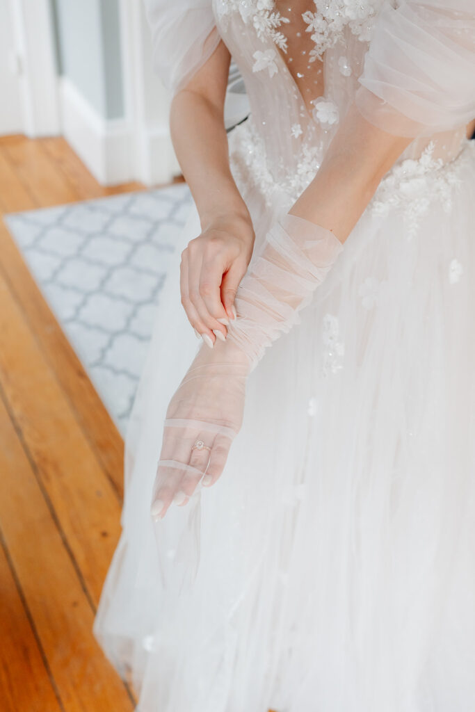 a candid wedding photo of the bride putting her gloves on