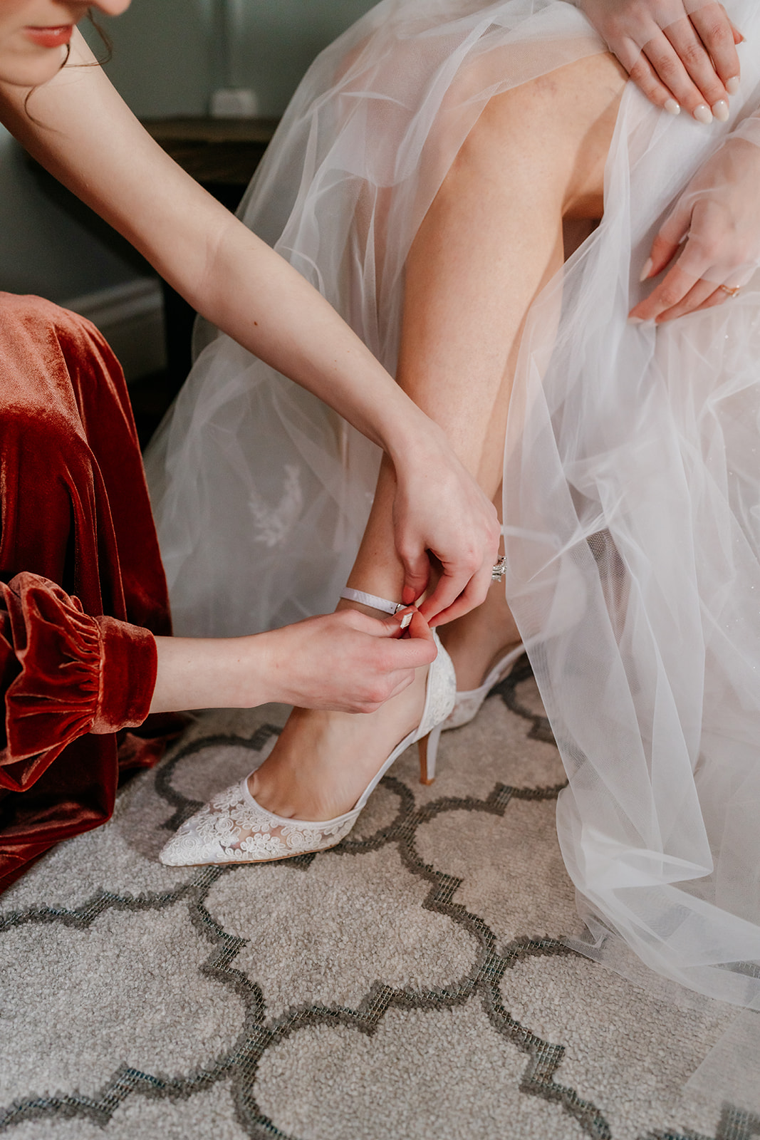 maid of honour helping the bride put on her wedding shoe