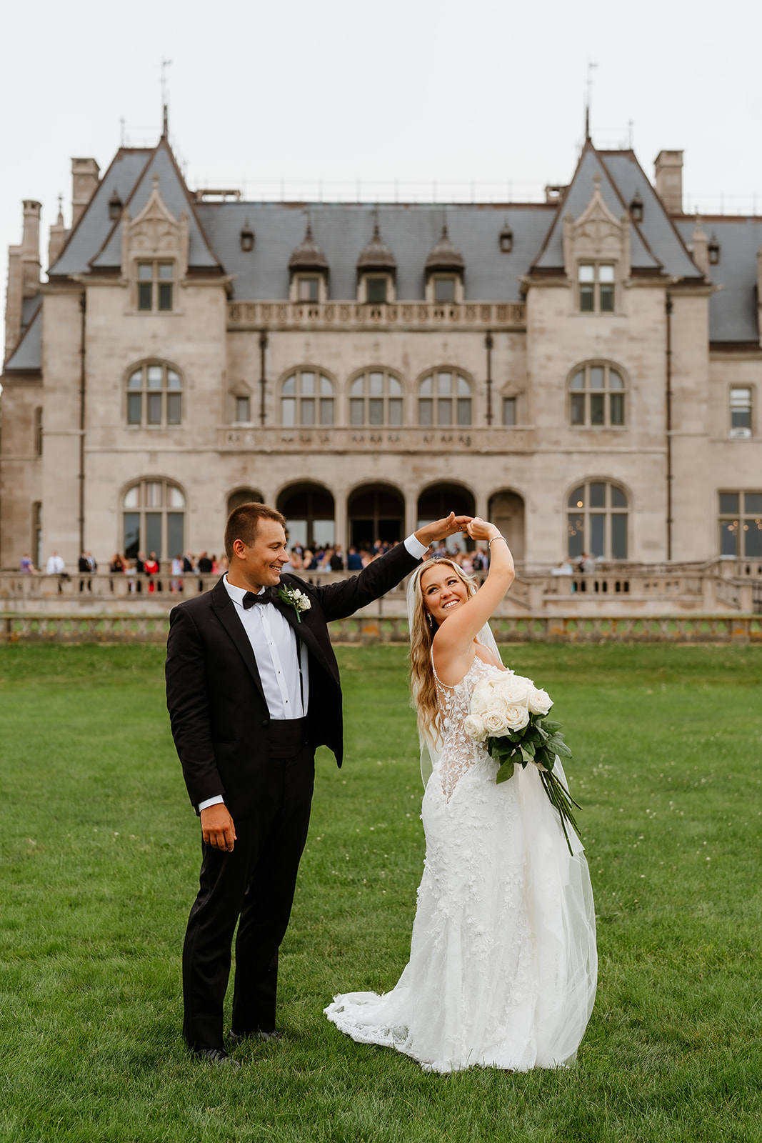 groom and bride dancing in front of Ochre Court In Newport