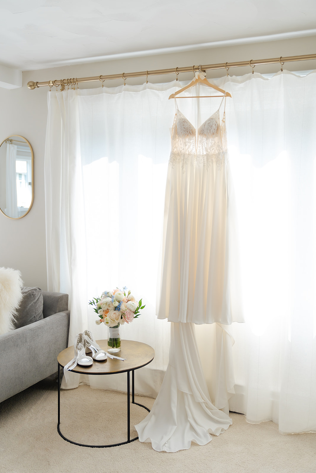 wedding dress hanging against the window at the bridal suite